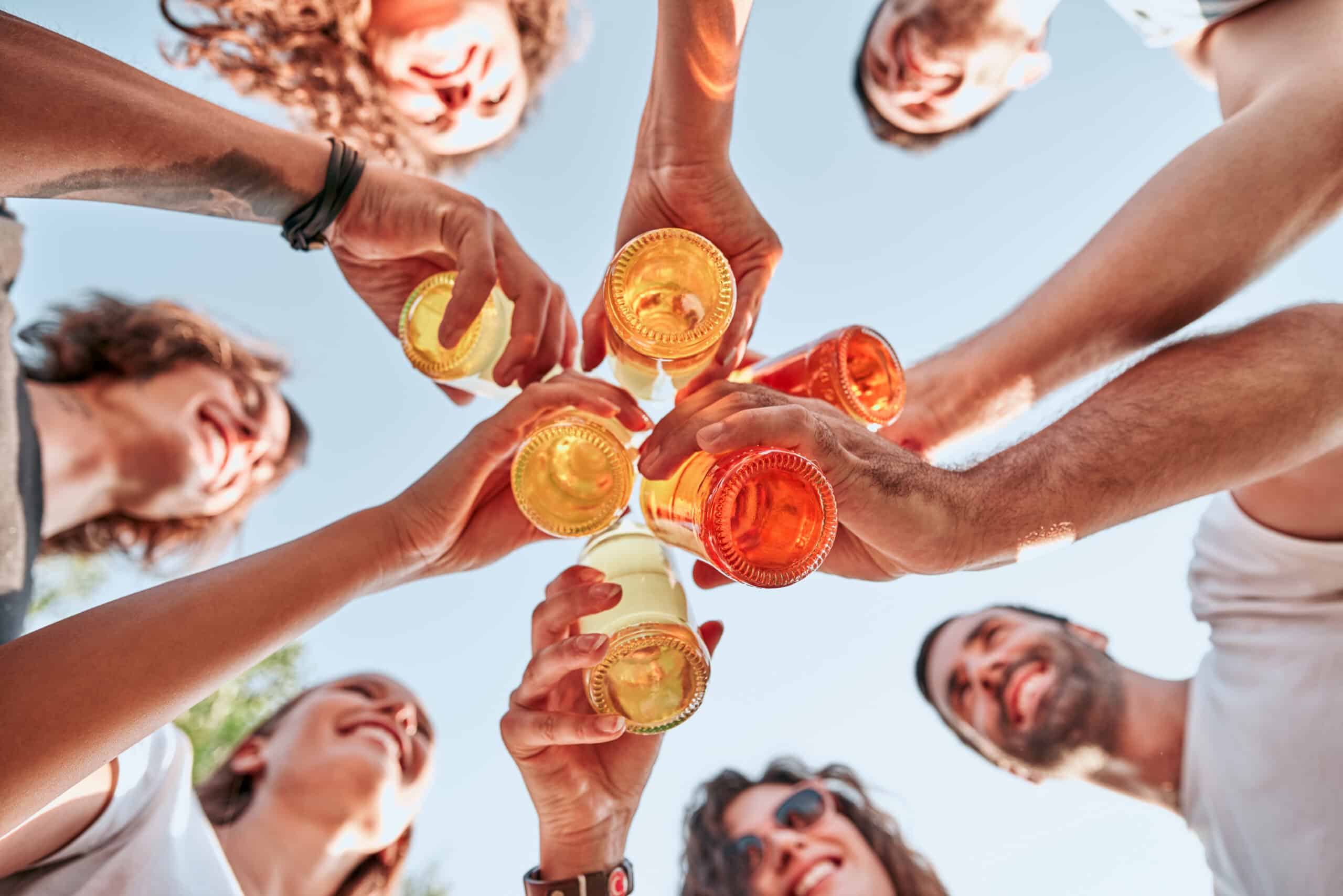 bottom view of group of happy young people clinking bottles of beer